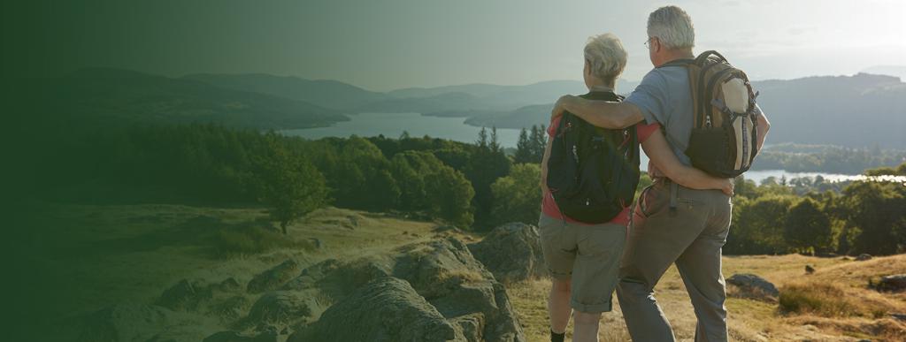 pensions-banner-no-text_V2_1440x540.jpg (Rear View Of Senior Couple Standing At Top Of Hill On Hike Through Countryside In Lake District UK)