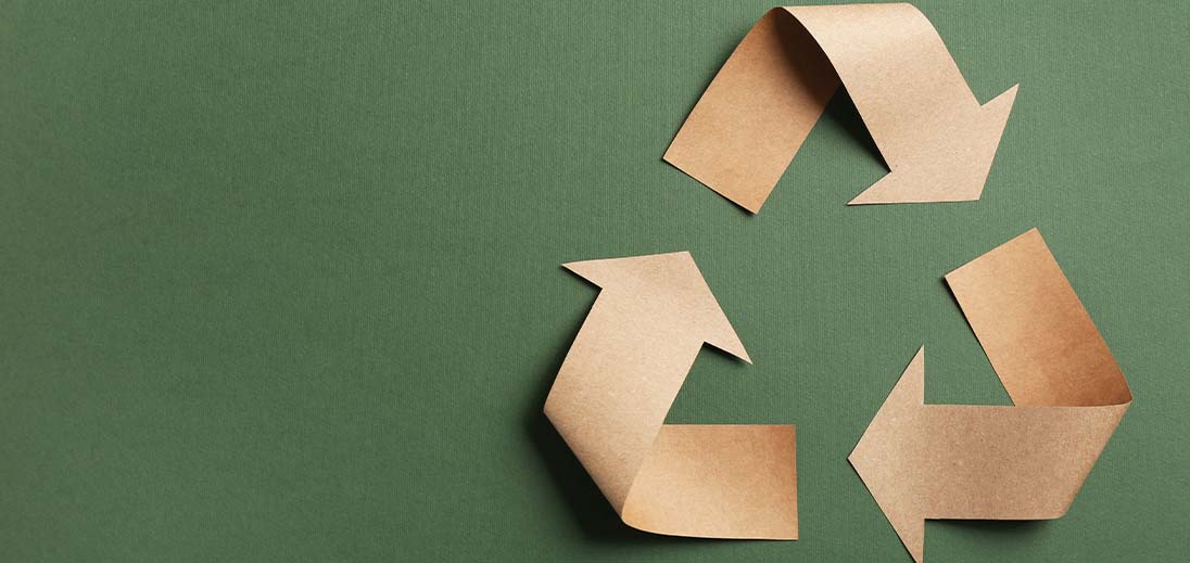 The recycling symbol made out of recycled paper on a green background.