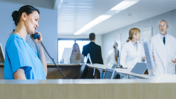 Infirmière au téléphone près du comptoir d'un hôpital application Coala Coversafe