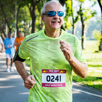 Un homme souriant d'âge moyen, portant un t-shirt vert fluo et des lunettes de soleil, court en plein air avec un dossard de marathon imprimé sur Polyart Laser Soft